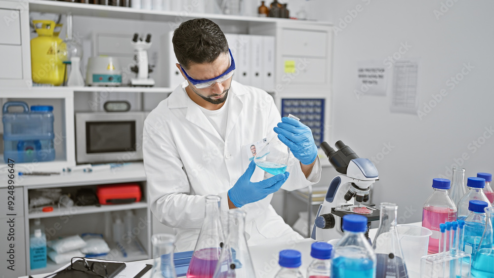 Handsome man conducting experiments in a laboratory setting, surrounded by scientific equipment. Handsome man conducting experiments in a laboratory setting, surrounded by scientific equipment.
