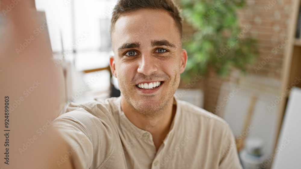 A cheerful young hispanic man taking a selfie indoors with a natural, confident smile. A cheerful young hispanic man taking a selfie indoors with a natural, confident smile.