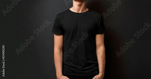 Close-up of a man wearing a plain black t-shirt against a dark background, perfect for fashion, apparel marketing, or product mockups, emphasizing simplicity and versatility in branding and promotiona