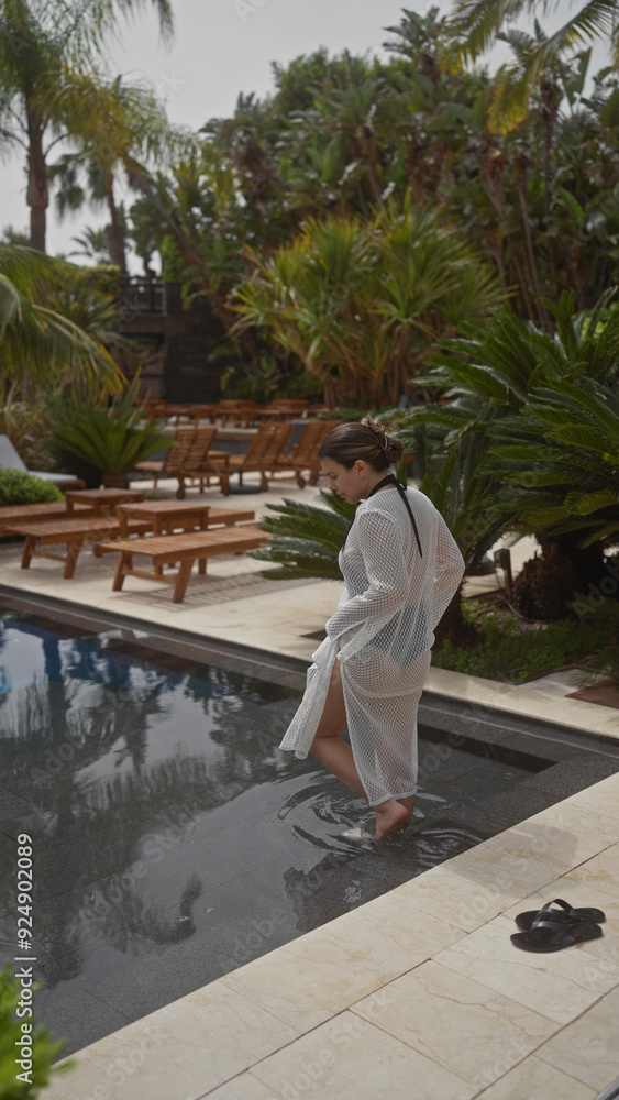 A young woman relaxes by a serene pool at a luxurious bali resort, surrounded by tropical foliage. A young woman relaxes by a serene pool at a luxurious bali resort, surrounded by tropical foliage.