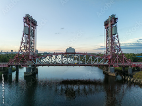 Steel lift bridge spanning river at sunset with industrial factories photo