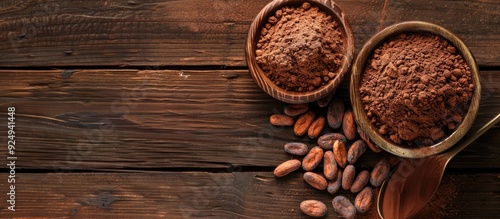 Cocoa powder in a bowl and cocoa beans on a white wooden background top view with copyspace Common ingredients for sweets baked goods and beverages