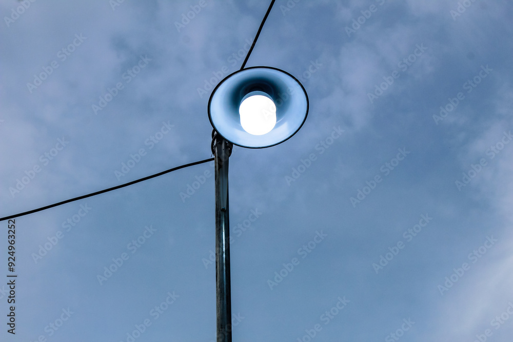 Selective focus street lights connected by cables with blue sky background in the park during the day Selective focus street lights connected by cables with blue sky background in the park during the day