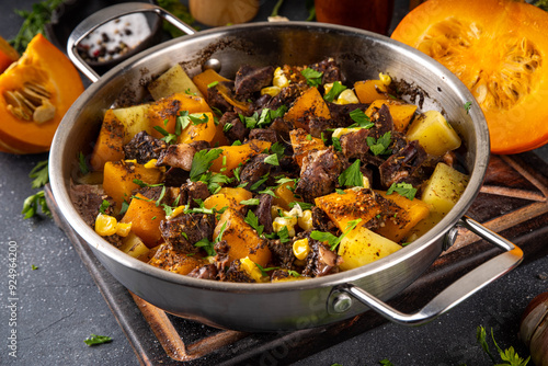 Warm pumpkin stew with potato and beef meat, comfort autumn dinner balanced food, with ingredients on kitchen table photo