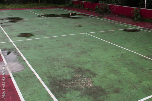 Selective focus abandoned badminton or tennis or soccer fields with water puddles during the day