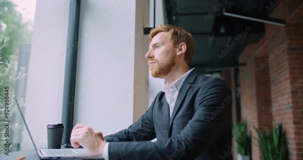 Smart Caucasian male actively typing on keyboard of new laptop. Looking outside window. Thinking about best possible reply to message. Considering about something important. Planning meeting.