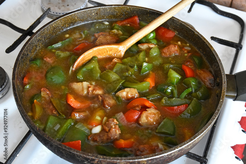 Goulash heated in a pan with a spoon