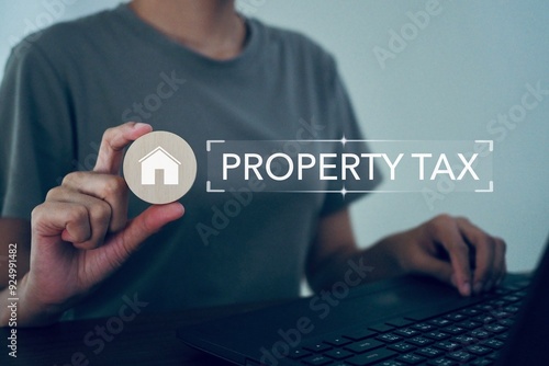 Property taxes with houses and residences. Business woman's hand holds a circular wooden block with a house on top.