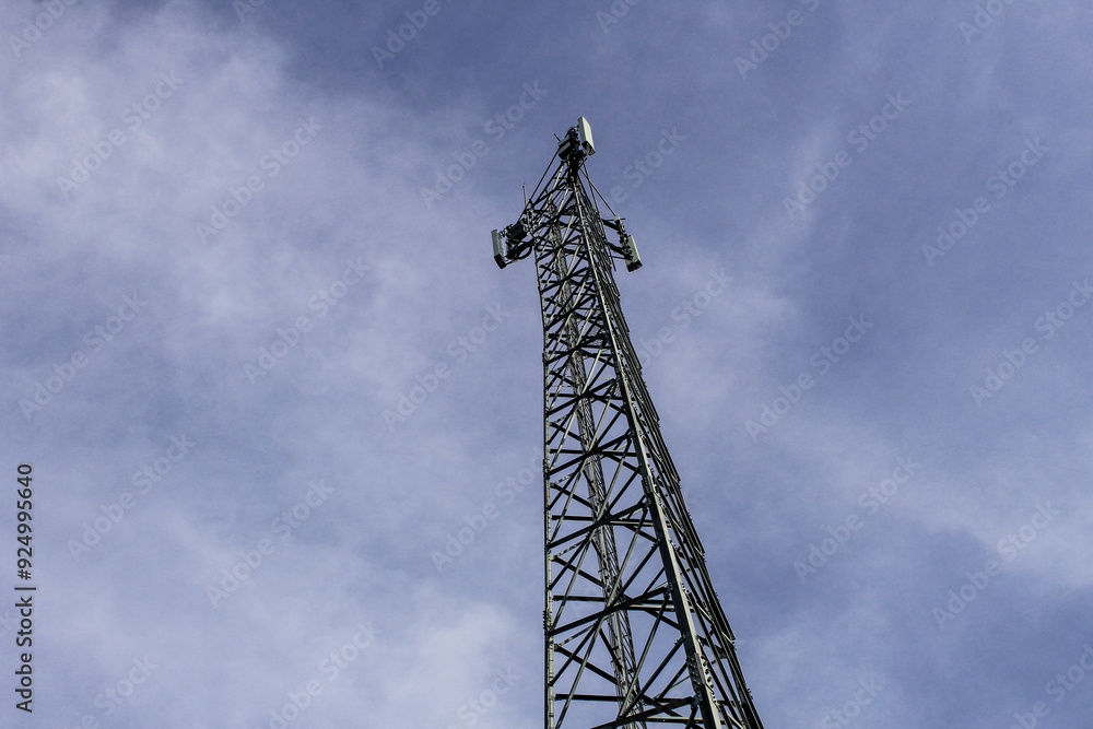Selective focus of telecommunications towers with a background of bright blue sky with clouds and trees during the day Selective focus of telecommunications towers with a background of bright blue sky with clouds and trees during the day