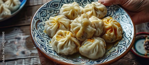 A hand holds up a hot Khinkali dumpling on a plate of Georgian cuisine with copy space image