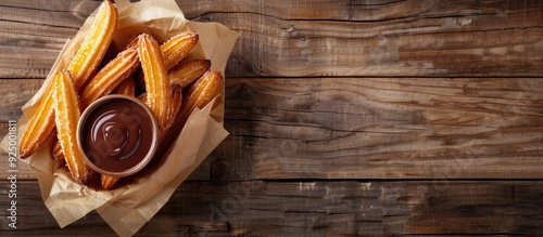 Churros with warm chocolate sauce displayed on a rustic wooden table with ample copy space image