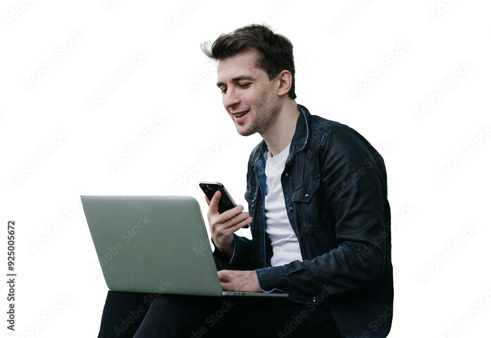 Handsome brunette cheerful male sitting on grass against transparent background with laptop making video call holds phone smiling having break remote working. man talking with friend via internet. Handsome brunette cheerful male sitting on grass against transparent background with laptop making video call holds phone smiling having break remote working. man talking with friend via internet.