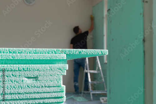 Indoor thermal insulation materials close-up selective focus. Out of focus insulation specialist installing XPS (Extruded Polystyrene) boards on the wall. 