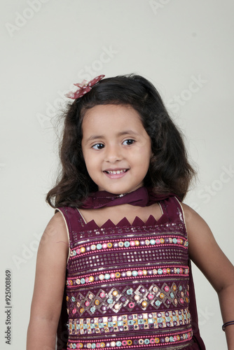  A delightful little girl with sparkling eyes, breaking into a wide, infectious smile. Her expression radiates pure happiness and innocence.