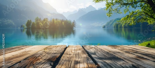 A wooden table set against a blurred lake and park backdrop provides ample copy space for showcasing an advertisement alongside the serene lake and majestic mountains