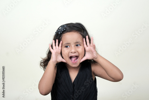  A delightful little girl with sparkling eyes, breaking into a wide, infectious smile. Her expression radiates pure happiness and innocence.