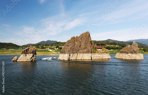 Danyang-gun, Chungcheongbuk-do, South Korea - June 13, 2022: Summer view of tourists on a motor boat sailing on Namhan River under Dodamsambong Peaks with a pavilion photo