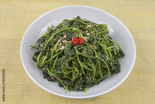 Close up of seasoned chwinamul with red pepper on white dish and cloth, South Korea