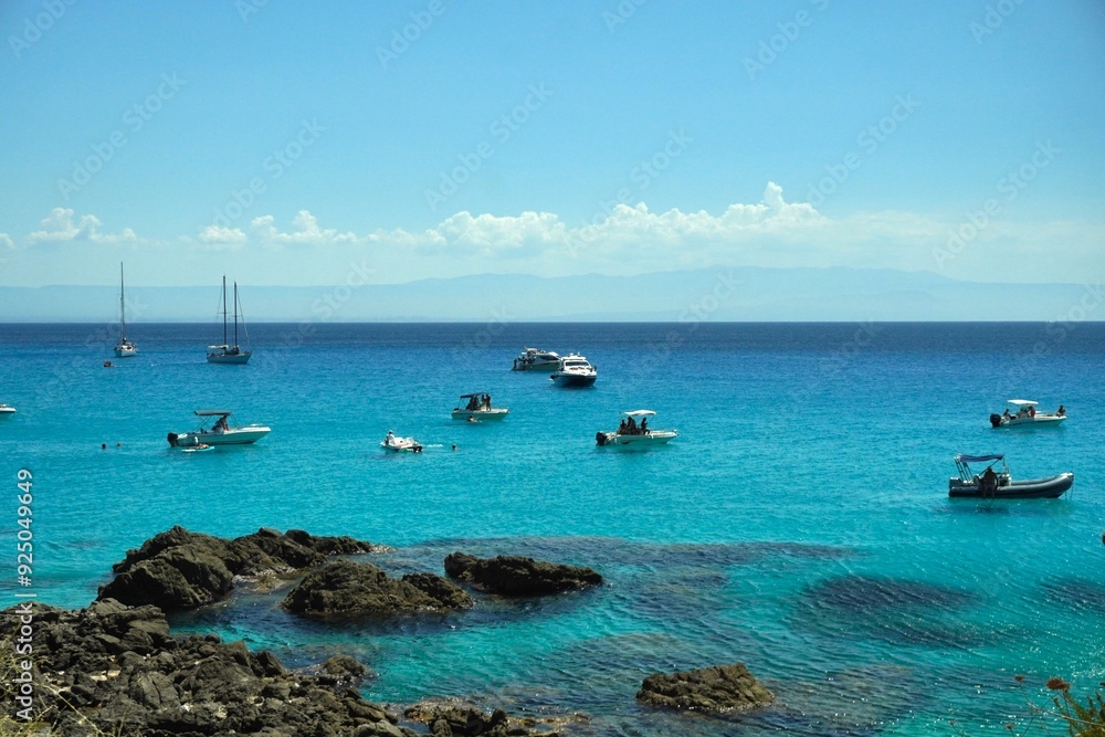 Fototapeta premium Boats standing or slowly floating along the shore seem to hang in the air, their reflections on the surface of the water create the illusion of flight. The blue of the sea amazes with its purity.