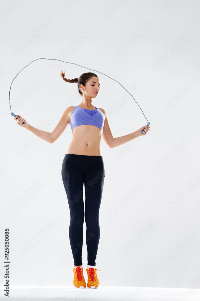 Girl, skipping rope and jump in studio for fitness or improve endurance, agility training and physical cardio for weightloss. Woman, white background and gym equipment for muscle, workout or exercise Girl, skipping rope and jump in studio for fitness or improve endurance, agility training and physical cardio for weightloss. Woman, white background and gym equipment for muscle, workout or exercise