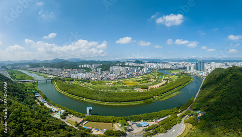 Taehwa-dong, Jung-gu, Ulsan, South Korea - July 30, 2022: Aerial and panoramic view of Sibli Pine Forest and Taehwagang National Garden near Taehwa River aginst apartments in summer photo