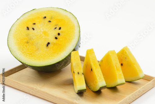 Close-up of a watermelon and fours slices with yellow section and black seeds on wood tray against white background, South Korea photo