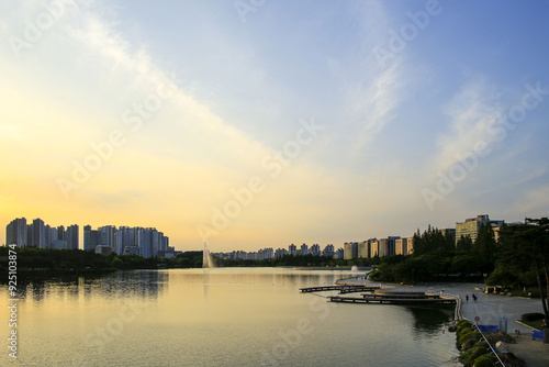 Ilsandong-gu, Goyang-si, Gyeonggi-do, South Korea - June 21, 2022: High angle and sunset view of Ilsan Lake Park with fountain against apartments in summer