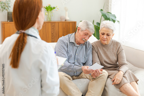 Female doctor examining older senior couple in doctor office or at home. Old woman man patient and doctor have consultation in hospital room. Medicine healthcare medical checkup. Visit to doctor