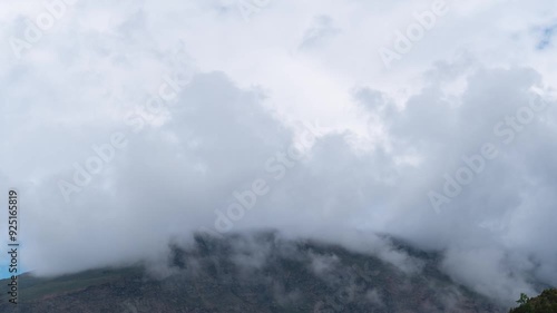 4K Time-lapse shot of dark monsoon stormy clouds above the Himalayan mountain peak as seen from Keylong in Lahaul, Himachal Pradesh, India. Clouds move above the mountains during monsoon. photo