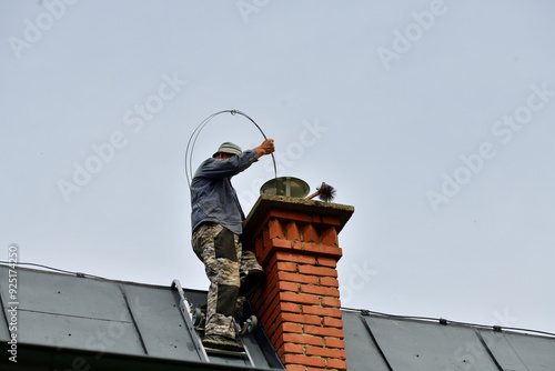 Traditional manual method of cleaning the chimney on the roof photo