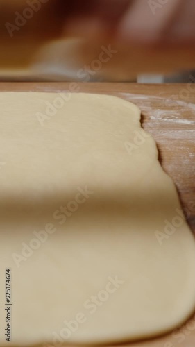 Wallpaper Mural Vertical video. Carefully Rolling Dough to Desired Thickness with a Wooden Rolling Pin, Preparing for Filling. Torontodigital.ca