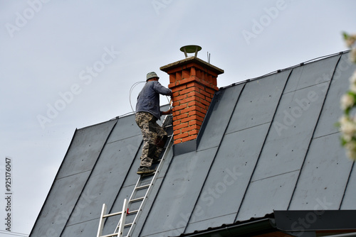 
The roof roofer climbs up the ladder to the roof of the house to fix sheet metal roof
