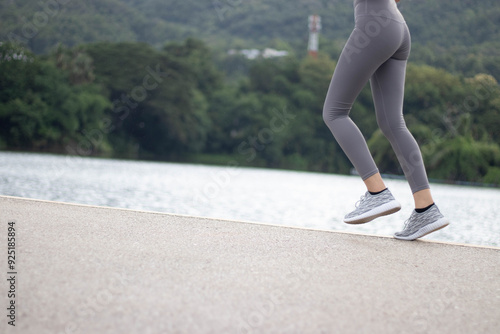 A woman is jogging on the edge. A lake in the middle of the city that is calm and relaxing on your holiday mornings to promote good health for sportsmen and athletes.