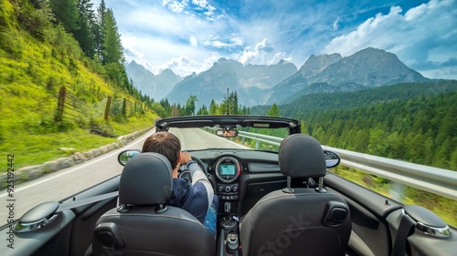 Back view of young caucasian man driving cabrio in summer Mountains