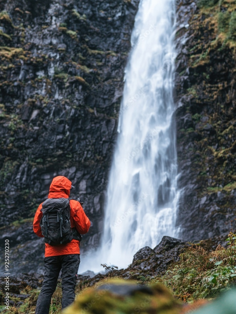 Hiker Standing in Awe of a Majestic Waterfall Hiker Standing in Awe of a Majestic Waterfall