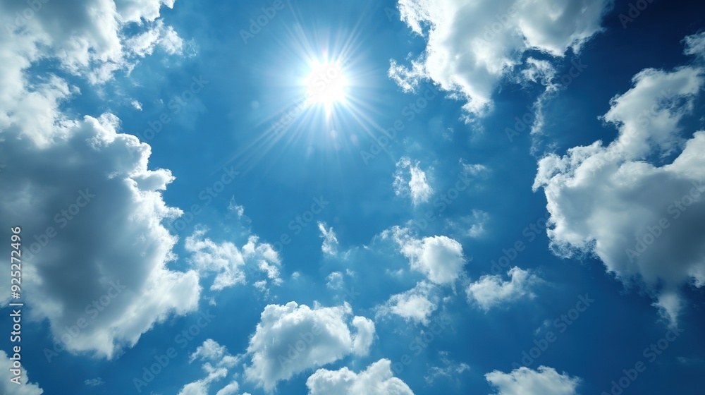 A bright sun shines down through fluffy clouds on a clear blue sky, creating a serene and uplifting atmosphere A bright sun shines down through fluffy clouds on a clear blue sky, creating a serene and uplifting atmosphere