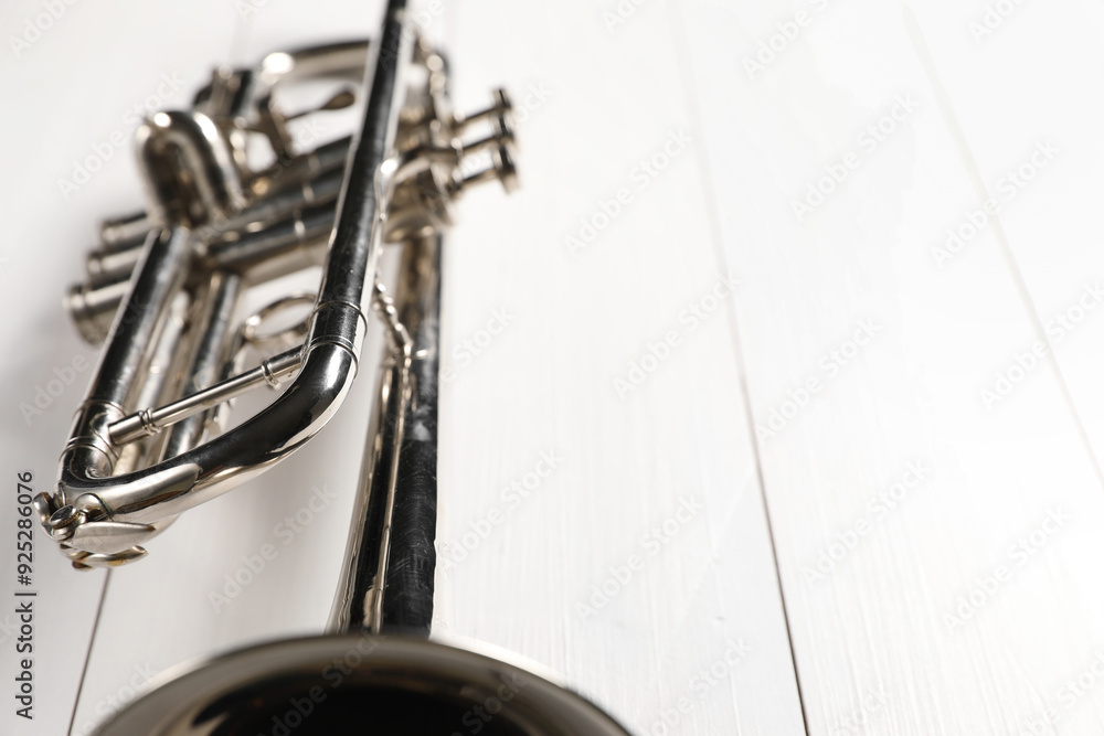Obraz premium One trumpet on white wooden table, closeup. Space for text