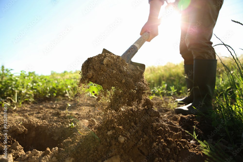 Fototapeta premium Farmer digging soil with shovel on sunny day, closeup