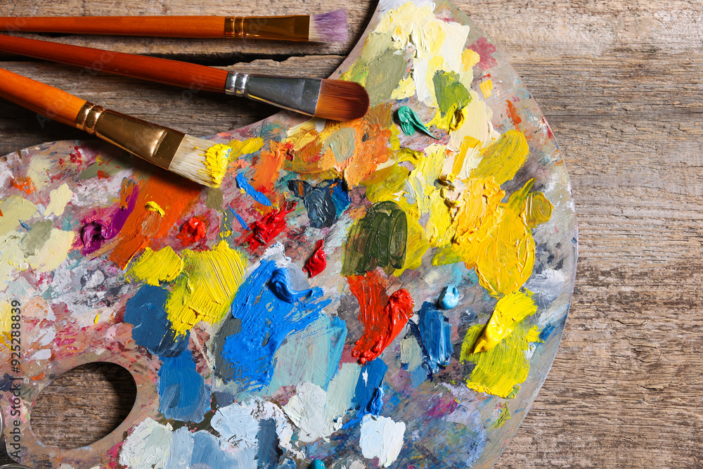 Obraz premium Artist's palette, brushes and paints on wooden table, flat lay