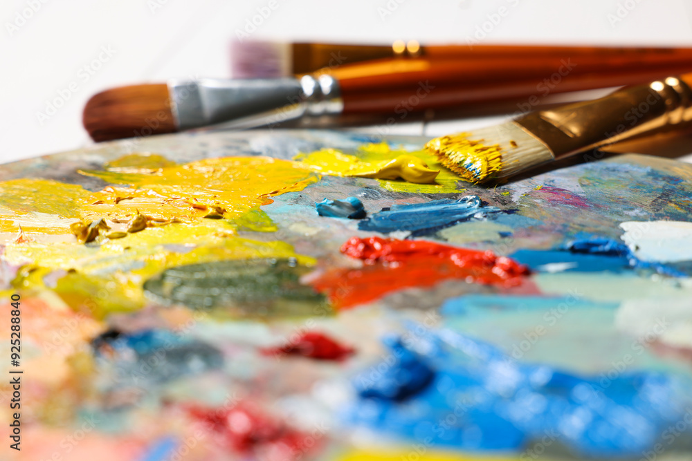 Artist's palette, brushes, paints on table, closeup Artist's palette, brushes, paints on table, closeup