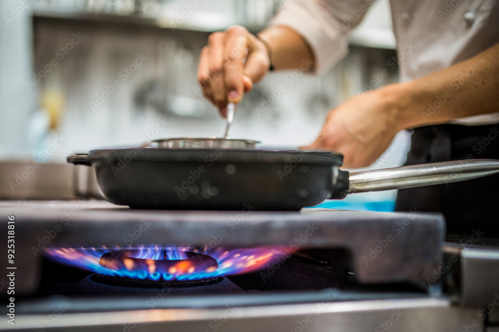 Chef stirring sauce in pan on gas stove in professional kitchen Chef stirring sauce in pan on gas stove in professional kitchen