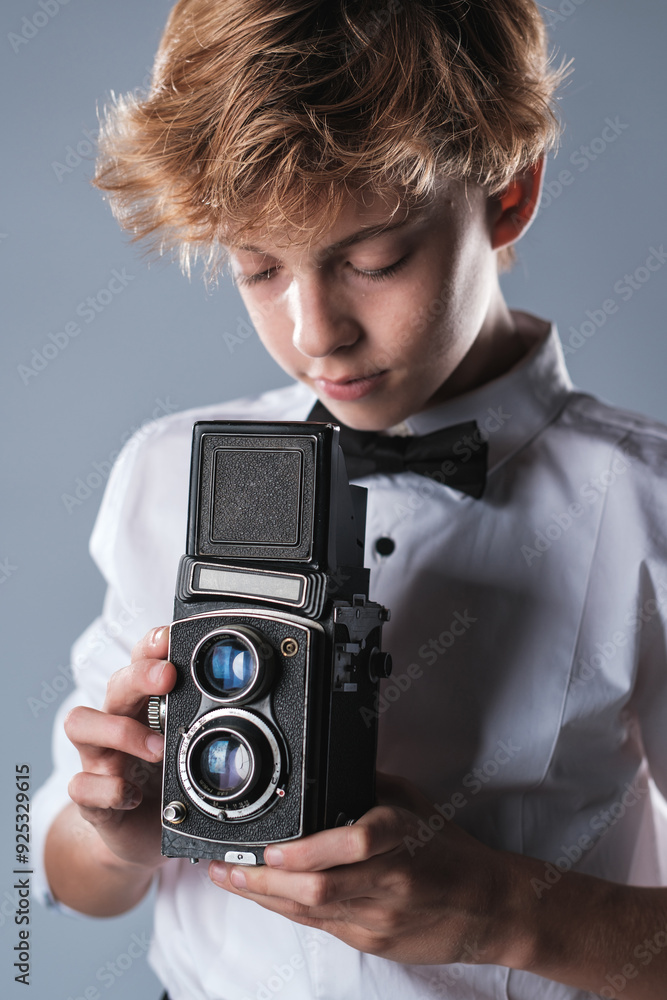 Preteen boy in white shirt and bow tie holding vintage photo camera Preteen boy in white shirt and bow tie holding vintage photo camera