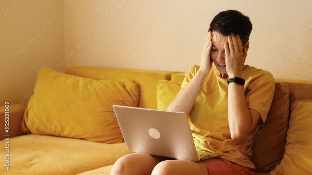 The girl was upset and covered her face with her hands in surprise and shock. A young Caucasian woman with short modern haircut is sitting at home working using a laptop. Work from home and online stu The girl was upset and covered her face with her hands in surprise and shock. A young Caucasian woman with short modern haircut is sitting at home working using a laptop. Work from home and online stu