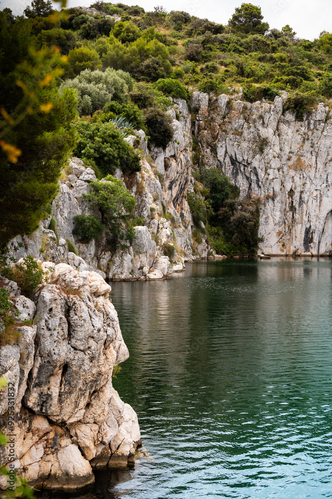 Vertical, stone cliffs of Zmajevo Oko lake in the small town of Rogoznica, Croatia, overgrown in bush and vegetation Vertical, stone cliffs of Zmajevo Oko lake in the small town of Rogoznica, Croatia, overgrown in bush and vegetation