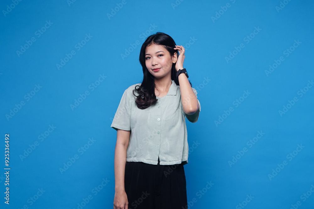 Cute funny attractive girl with straight fair hair pinching her cheeks and smiling, wearing green shirt, posing against blue background Cute funny attractive girl with straight fair hair pinching her cheeks and smiling, wearing green shirt, posing against blue background