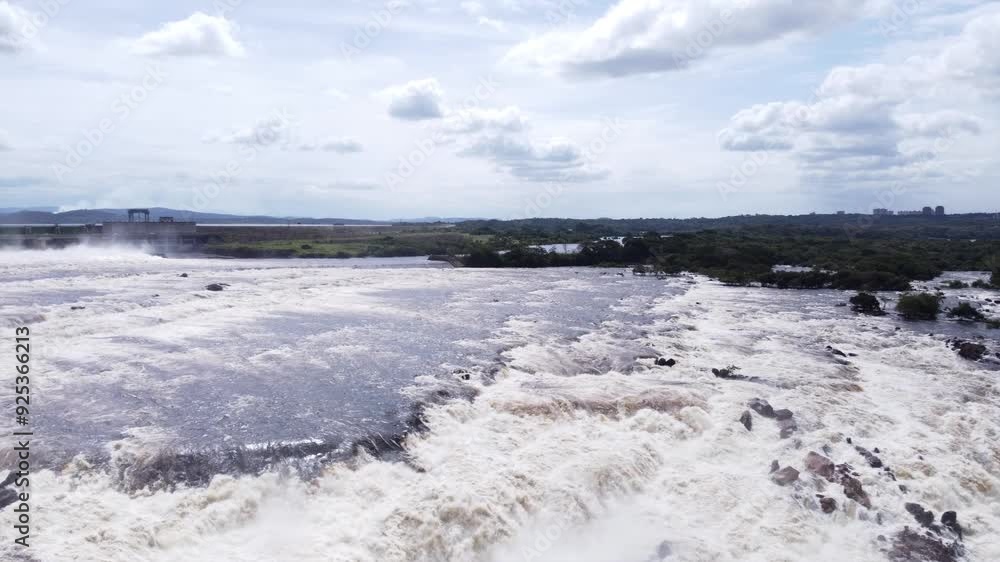 Starting with the mesmerizing waterfall, the camera gradually pans to reveal the imposing dam that harnesses its energy Starting with the mesmerizing waterfall, the camera gradually pans to reveal the imposing dam that harnesses its energy