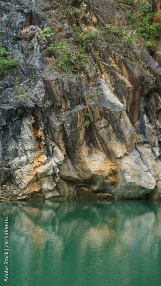 An image of a rocky cliff with a mix of gray and reddish hues, surrounded by greenery. An image of a rocky cliff with a mix of gray and reddish hues, surrounded by greenery.