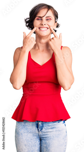 Beautiful young woman with short hair wearing casual style with sleeveless shirt smiling with open mouth, fingers pointing and forcing cheerful smile