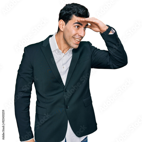 Handsome hispanic man wearing business clothes very happy and smiling looking far away with hand over head. searching concept.