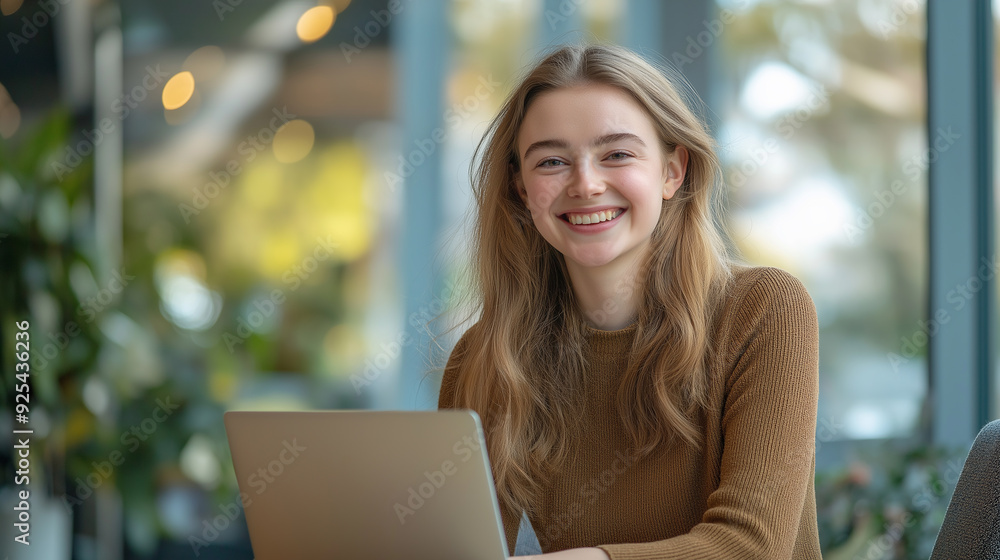 A young woman with long blonde hair smiles brightly while using a laptop in a cozy indoor setting, symbolizing productivity and happiness. A young woman with long blonde hair smiles brightly while using a laptop in a cozy indoor setting, symbolizing productivity and happiness.